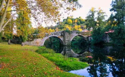 a stone bridge over a river in a park at Casa MENDEZ - ALLARIZ in Ourense