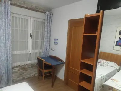a bedroom with a desk and a bed and a bed and a desk at Hostal Burbia in Villafranca del Bierzo