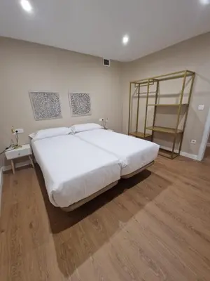 a large white bed in a room with a wooden floor at Apartamentos Turísticos MENCÍA in Monforte de Lemos