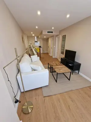 a living room with a white couch and a table at Apartamentos Turísticos MENCÍA in Monforte de Lemos