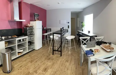a kitchen with a white refrigerator and a table with stools at Albergue a Carballeira in Villalba