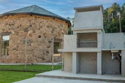 a stone building with a stone wall and a building at Pallozas Turísticas Ridicodias - A Vieira in Laza