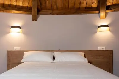 a bedroom with a bed with two pillows and two lights at Pallozas Turísticas Ridicodias - A Vieira in Laza