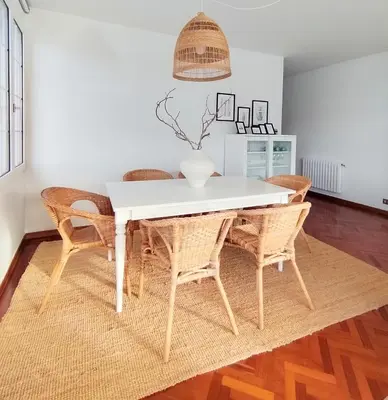 a dining room with a white table and wicker chairs at Sobre la Ría in Viveiro