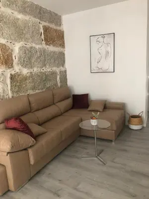 a living room with a brown couch and a brick wall at A esmorga in Ourense