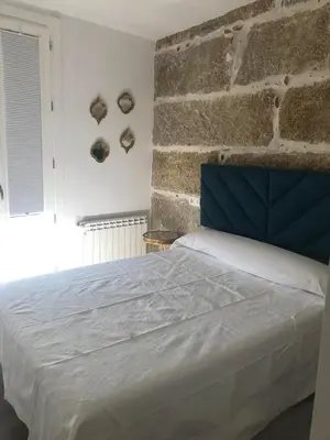 a bedroom with a white bed and a brick wall at A esmorga in Ourense