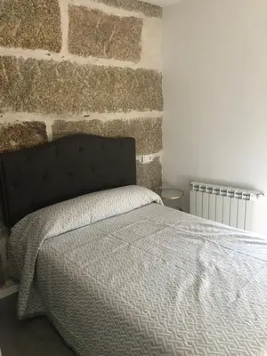 a bed in a bedroom with a brick wall at A esmorga in Ourense