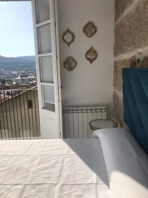 a bedroom with a bed and a balcony with a window at A esmorga in Ourense
