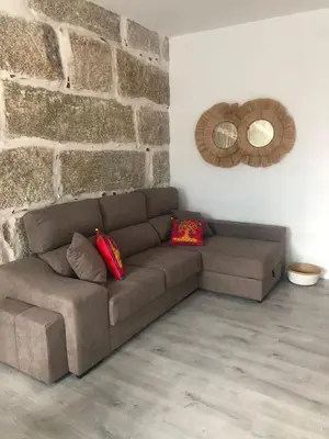 a brown couch in a room with a brick wall at A esmorga in Ourense