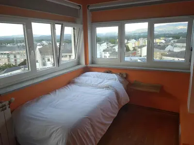 a bed in a room with three windows at Vivienda A Travesía Dos Soños in Sarria