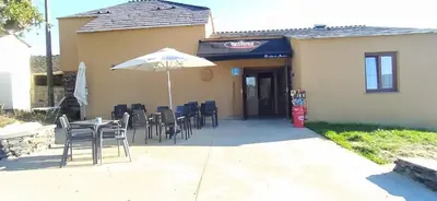 a patio with a table and chairs and an umbrella at O Lar do Alecrín in Friol