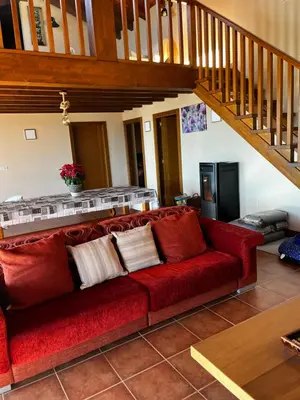 a red couch in a living room with a staircase at Lobetios - Casa rural in Parada de Achas