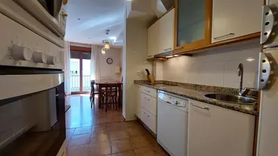 a kitchen with white cabinets and a sink and a table at Casa Rural Maria in Molinaseca