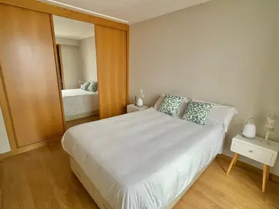 a bedroom with a large white bed and a mirror at Estudio céntrico 1 con terraza y parking privado in Ourense