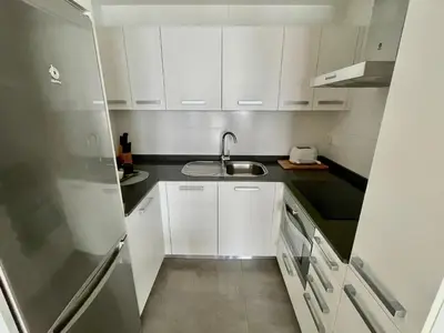 a small kitchen with white cabinets and a sink at Estudio céntrico 1 con terraza y parking privado in Ourense