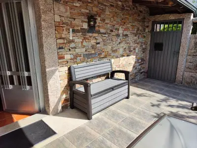 a bench sitting on a patio next to a brick wall at Exclusiva Casa Rural Mariano con acceso directo al rio in Baralla