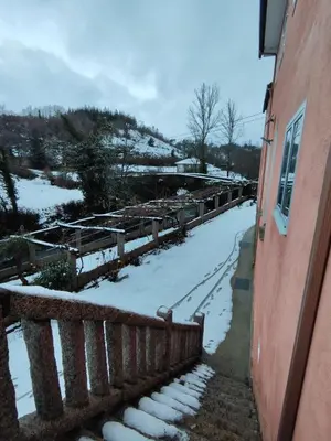 a snow covered yard with a fence next to a building at Exclusiva Casa Rural Mariano con acceso directo al rio in Baralla