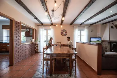 two people sitting at a table in a living room at Exclusiva Casa Rural Mariano con acceso directo al rio in Baralla