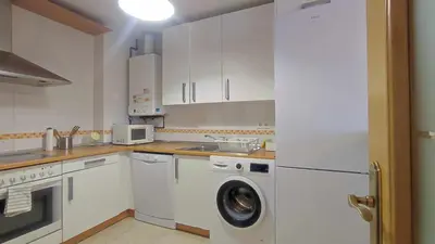 a kitchen with white cabinets and a washing machine at Apartamento en Miño in A Coruña
