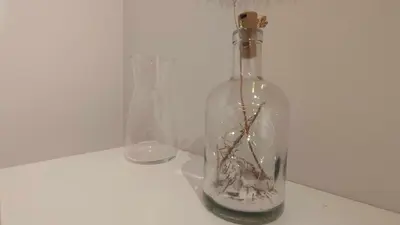 a bottle with branches in it on a table with two vases at Apartamento en Miño in A Coruña