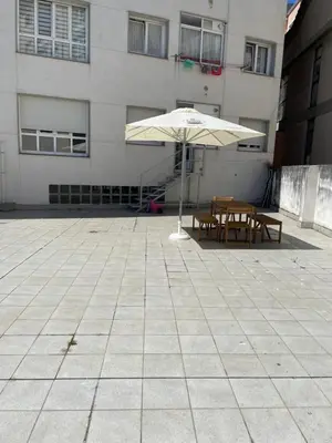 an umbrella and two tables in front of a building at Apartamento vacacional foz in Foz
