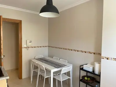 a dining room with a white table and chairs at Apartamento vacacional foz in Foz