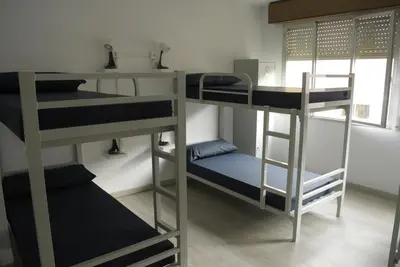 a room with three bunk beds and a desk at Albergue Trabazo in Silleda
