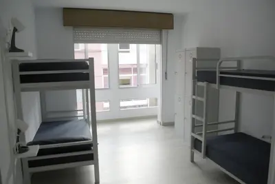 a room with three bunk beds and a window at Albergue Trabazo in Silleda