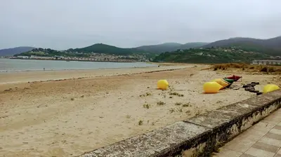 a beach with yellow inflatablefacts sitting on the sand at Piso luminoso y acogedor en primera línea de playa Covas Viveiro in Vivero