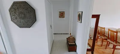 a hallway leading to a dining room with a clock on the wall at Piso luminoso y acogedor en primera línea de playa Covas Viveiro in Vivero