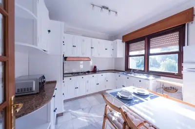 a kitchen with white cabinets and a table with chairs at Luminoso apartamento reformado en villa termal in Cuntis