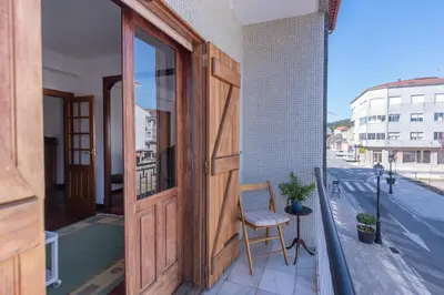 an open door on a balcony with a chair at Luminoso apartamento reformado en villa termal in Cuntis