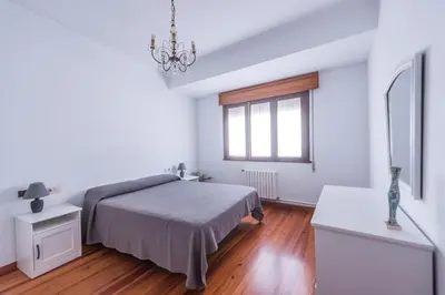 a white bedroom with a bed and a window at Luminoso apartamento reformado en villa termal in Cuntis