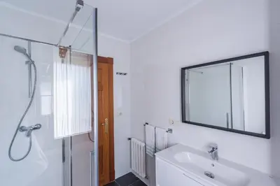 a white bathroom with a sink and a mirror at Luminoso apartamento reformado en villa termal in Cuntis