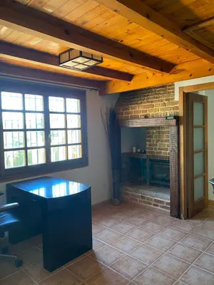 a living room with a stone fireplace and a desk at Agradable chalet rústico in Cambre