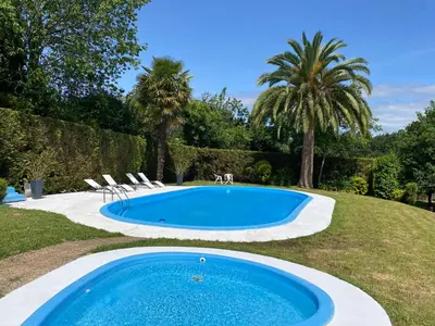 a pool in a yard with chairs and a palm tree at Casita rústica in Cambre