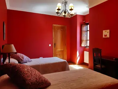 a red bedroom with two beds and a chandelier at Casa Rural dos Chaos in Arnoia
