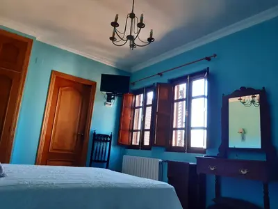 a bedroom with blue walls and a bed and a mirror at Casa Rural dos Chaos in Arnoia