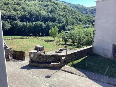 a stone wall next to a field with a mountain at Pension Casa Simon in Tríacastela