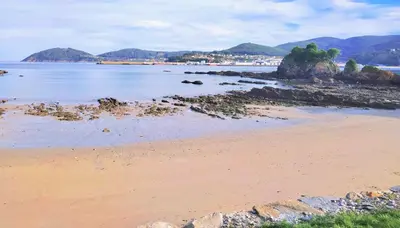 a beach with rocks and water and mountains in the background at The Cliffs - Mansión del Indiano I in Viveiro