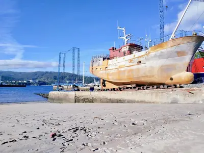 a boat is docked next to the beach at The Cliffs - Mansión del Indiano I in Viveiro