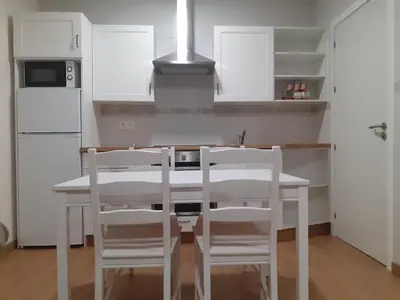 a kitchen with white cabinets and a white table and chairs at LOFT FRIOL in Friol