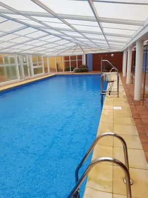 a large swimming pool with blue water in a building at En primera linea de la playa Rapadoira in Foz