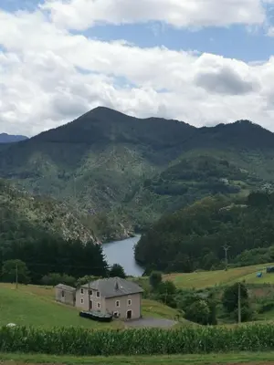 a house in a field with a lake and mountains at La casona El Espín in Serandinas