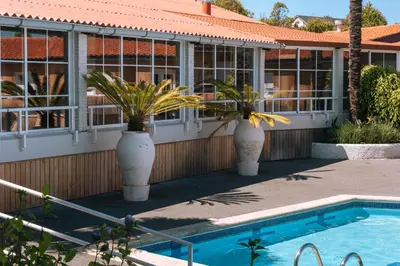 a house with a swimming pool and two large vases with palm trees at Makkan Club in Oleiros