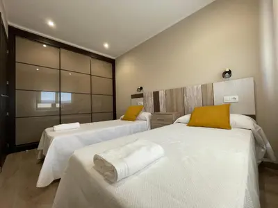 a bedroom with two beds with white sheets and yellow pillows at Casa Os Chocolateiros in Ourense