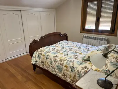 a bedroom with a bed with a floral bedspread and a lamp at As Pias in Pontevedra