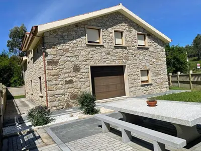 a stone house with a garage and a bench at As Pias in Pontevedra
