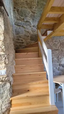 a wooden staircase in a room with a stone wall at Casa Leirón in Parada del Sil