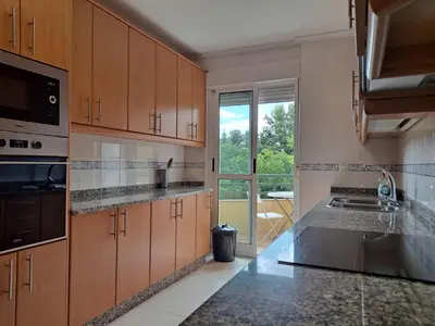 a kitchen with wooden cabinets and a large window at Apartamento con vistas, amplio y luminoso in Monforte de Lemos